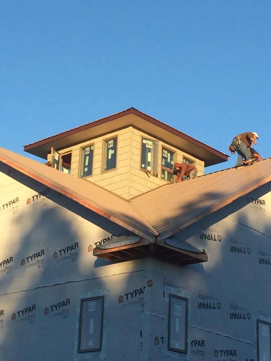 Roofers working around a rooftop cupola on a new metal roof at sunset — Roof Waterproofing in Roscoe by Roofing Brothers